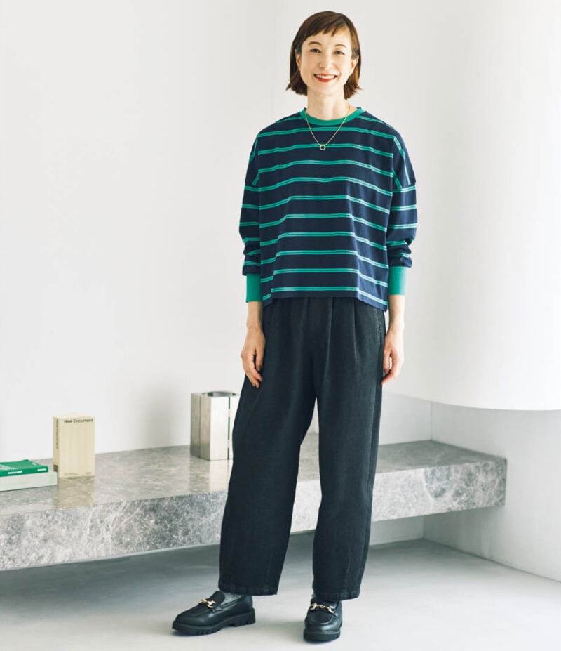主役のデニムは、立体フォルムをつくるウエストのタック使いと裾を絞ったデザインがポイント。ブラックデニムにグリーンのボーダーが映えるTシャツを合わせてきれいめカジュアルに。デニム¥2,420、ボーダーTシャツ¥1,419（ともにシーズン リーズン バイ リン アンド レッド／しまむら）　ネックレス、靴（ともにしまむら参考商品）