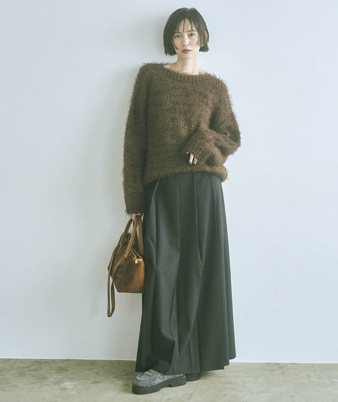 柔らかな風合いと優しさが魅力のモヘアニットには、ハンサムなフロントプリーツのストライプ柄スカートがマッチ。黒で引き締めてスタイリッシュに。ニット¥20,680（トリコット ジーン マルク／セムインターナショナル）　スカート¥29,700（エモエレ／アダム エ ロペ）　ピアス¥26,400（キリハ）　バッグ¥27,500（オウレンティ／セムインターナショナル）　シューズ¥33,000（ALM.）