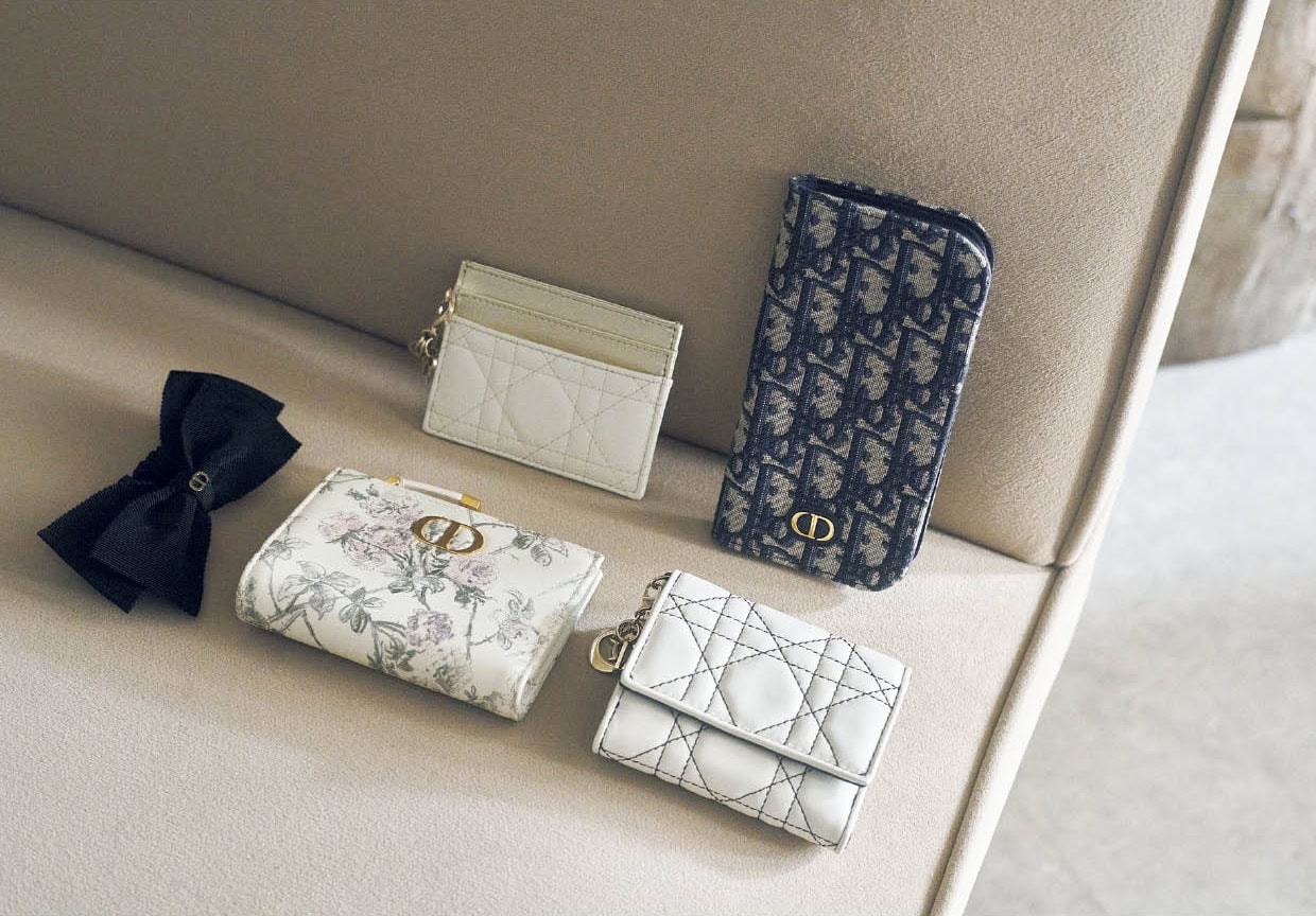 上段右から、“ディオール オブリーク”ジャカードを使用した手帳型。内側にはカード入れやポケットもあって機能的。スマホケース※iPhone16 Pro用￥97,000、アイボリー×ゴールドの洗練された配色と“カナージュ”ステッチが上品。取り外し可能な“D.I.O.R.”チャームも華やか。カードケース［H8×W10.5×D0.5、カード入れ5］￥65,000、下段右から、白×黒のコントラストがスタイリッシュ。コンパクトな三つ折りで手のなじみもグッド。日本限定。ウォレット［H8.5×W10×D2.5、カード入れ4］￥110,000、ムッシュのお気に入りの花を繊細なタッチと優しい色合いで描いたファンタジックなデザイン。日本限定。ウォレット［H9×W12×D2、カード入れ6］￥125,000、大きなリボンと“CD”シグネチャーを優雅なアクセントに。ヘアアクセサリー￥68,000（すべてディオール／クリスチャン ディオール）