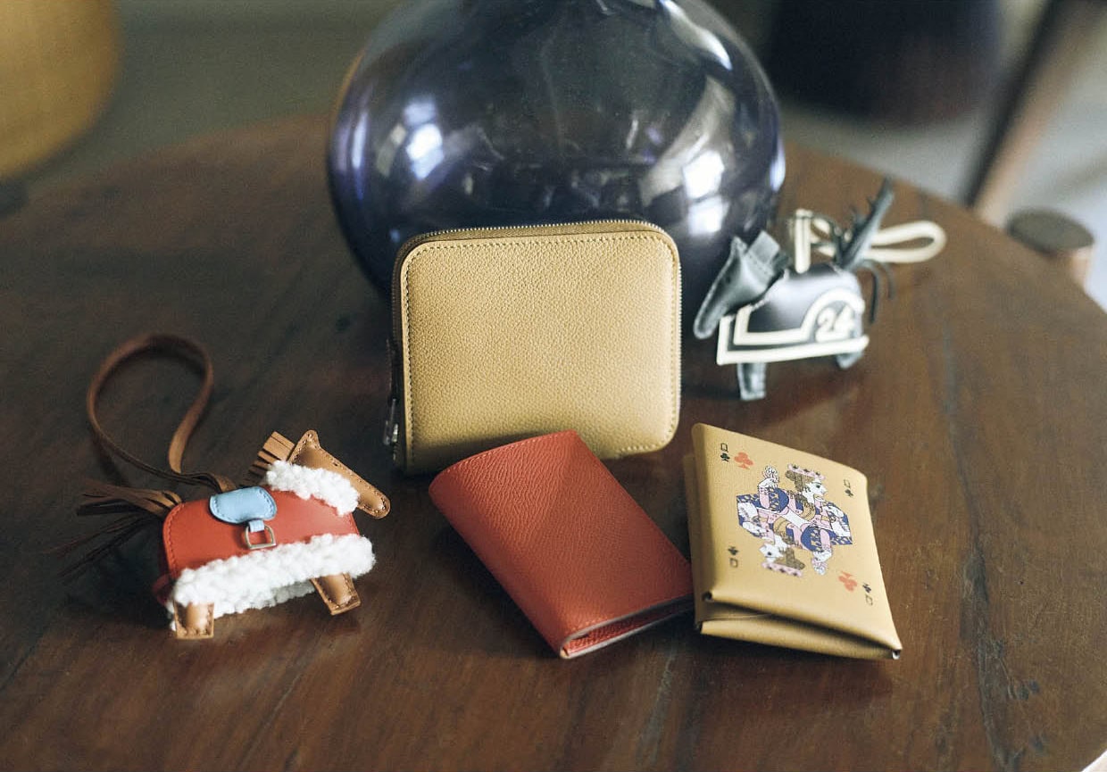 上段右から、たてがみや尾のフリンジなどの躍動感がたまらない馬チャーム。レーシングドレスの白のラインとナンバーがスポーティ。チャーム￥144,100、美しいレザーのシボが引き立つミニマルなスクエアシェイプ。ラウンドジップの開閉もスムーズ。ウォレット［H9.5×W11.5、カード入れ6］￥196,900、下段右から、トランプのクイーンをモチーフに、アートなセンスが息づくバランスと色使いはさすが。丸みのあるフォルムで気持ちよく手になじむ。ウォレット［H10.5×W7、カード入れ1、小銭入れ1］￥136,400、手に取るたびに元気になれるきれいな色。コンパクトで小ぶりのバッグにも収まりがいい。カードケース［H9.5×W7、カード入れ2］￥11 3,300、ふわふわのボアがついたケープを纏った姿にキュン。チャーム￥202,400（すべてエルメス／エルメスジャポン）