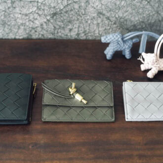 上段、犬と猫をモチーフに、細いコードを編み上げた手の込んだイントレチャート。心がなごむ可愛い佇まいと、優しいパステルカラーで春のムードを先取り。チャーム 各￥93,500、下段右から、スタイリッシュなライトグレー。後ろにカード入れが付いたスタンダードな仕様。柔らかなレザーで出し入れしやすい。カードケース［H8.2×W12×D0.5、カード入れ3］￥88,000、ゴールドカラーのノットをアクセントにしたシンプルさがグッド。前にフラップポケット、後ろにジッパー付きコイン入れとカードスロットが。［H8.6×W12.5×D1、カード入れ3］￥136,400、深みのあるグリーンがクラシカル。メタルのノットディテールがついたコンパクトな二つ折り。ウォレット［H11.5×W10×D1、カード入れ6］￥124,300（すべてボッテガ ・ヴェネタ／ボッテガ ・ヴェネタ ジャパン）