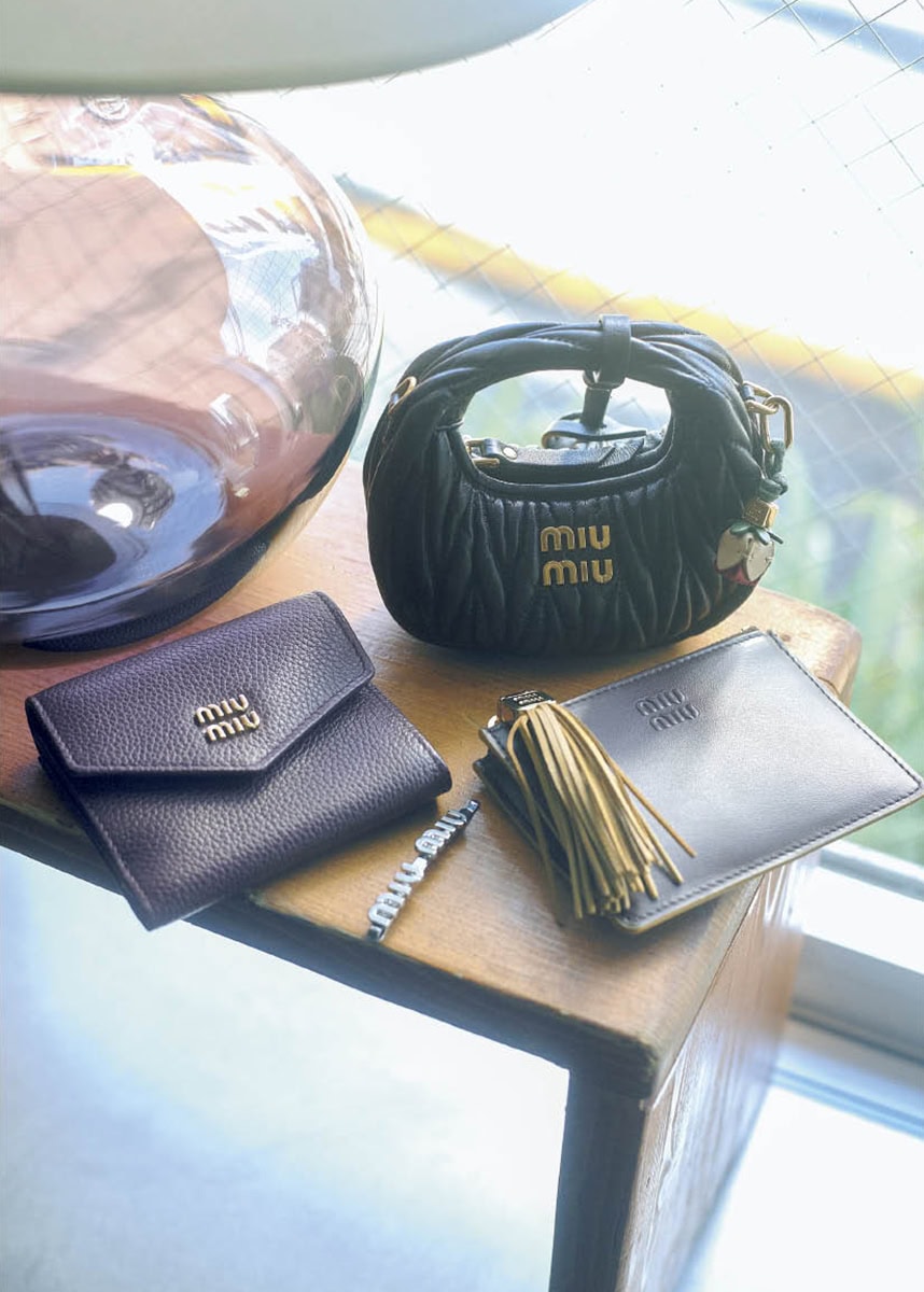 上から、細部まで精巧に再現された完成度の高さ。花のチャームまで揃っていてワクワク。バッグチャーム［H9・5×W12×D5］￥161,700、バッグチャームにつけたチャーム￥31,900、ボリューミーなフリンジとロゴ入りのメタルパーツがインパクト大。後ろにカードスロット、取り外し可能なキーリング付き。カードホルダー［H8×W11、カード入れ3］￥83,600、メタルのロゴをのせたフロントフラップと、きれいなシボのボルドーカラーがクラシカルで上品。ウォレット［H8×W9×D2、カード入れ3］￥88，000、アイコニックなロゴデザイン。ヘアピン￥52,800※すべて予定価格（ミュウミュウ／ミュウミュウ クライアントサービス）