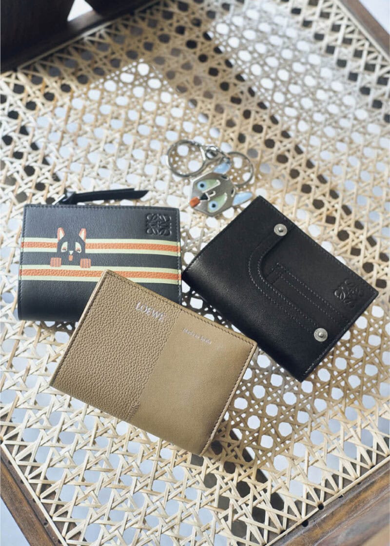 上から、ブルーの大きな目や耳、ぺろんと出した舌がファニー。シルバーカラーなので甘くなりすぎず、スタイリッシュにつけられそう。キーホルダー￥58,300、デニムのポケットやリベットを写したディテールが新鮮。美しいステッチを施した極上の仕上がりに職人技が宿る。ウォレット［H8・5×W11×D3、カード入れ6］￥115,500、オレンジ×アイボリーのダブルラインから顔を出す猫が愛らしい。インターシャ技法により耳や目、手などが立体的に浮かび上がる。ウォレット［H8・5×W11・4×D3、カード入れ6］￥115,500、シボとスムース、二つの表情の組み合わせがモダン。ウォレット［H8・5×W11・4×D3、カード入れ6］￥102,300（すべてロエベ／ロエベ ジャパン クライアントサービス）