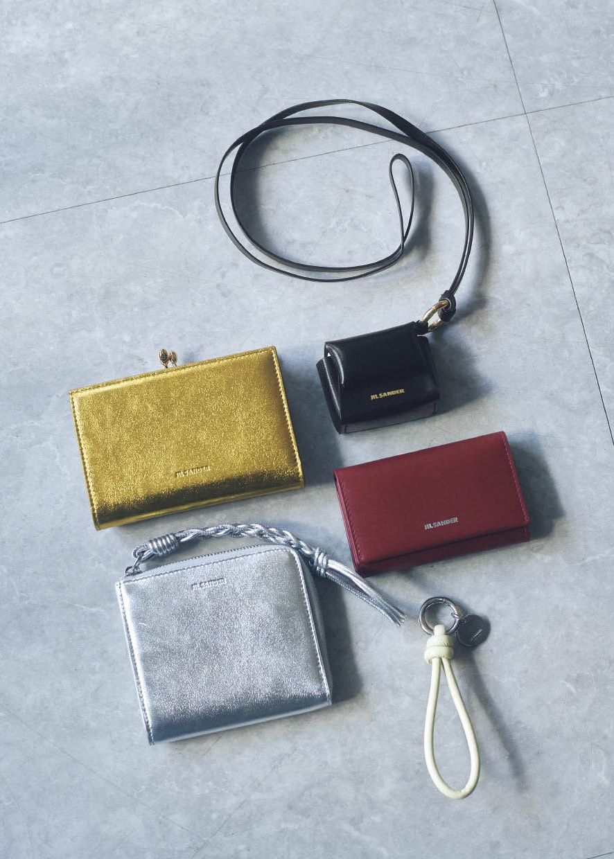 右上から時計回りに、アートピースのような存在感を放つ、クリーンなフォルムが秀逸。AirPodsケース［H5×W6×D3］￥85,800　都会的でスタイリッシュなダークレッド。キーケース［H6・5×W10・5×D1・5、カード入れ2］￥74,800、ボリュームのあるレザーコードを結んだシンプルさがグッド。キーリング￥53,900、メタリックな輝きが旬なスクエア形。手編みのストラップが洒落たアクセントに。ウォレット［H10×W11×D2、カード入れ6］￥96,800、黄みの強いゴールドカラーがさりげなく個性を発揮。シャープなフォルムがモダンながま口。ウォレット［H8・5×W12・5×D2、カード入れ8］￥184,800（すべてジル サンダー／ジルサンダージャパン）