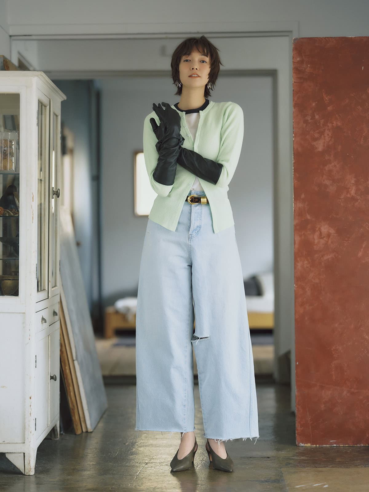 裾や部分的にあしらわれた程よいダメージ感がお洒落。デニムとトーンを揃えたカラーニットにレザーグローブでピリッと辛さを添えて。クラッシュデザインカーブデニム￥22,000（アングリッド）　トップス￥20,900（アイアワク）　ロングTシャツ￥17,380、レザーグローブ￥27,280（ともにオブラダ／シンチ）　ベルト￥70,400（デアンシュ／S&T）　シュシュ￥1,650（アネモネ／サンポークリエイト）　ピアス￥27,500（フミエタナカ／ドール）　カーキミュール￥20,700（ドゥーブル／サロン アダム エ ロペ）