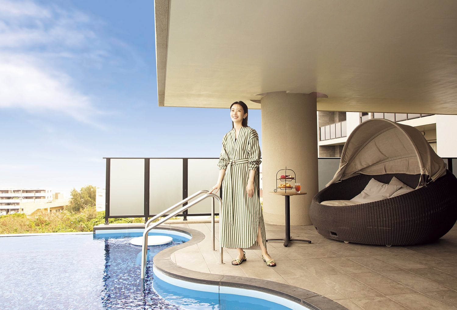 グランディスタイル沖縄読谷ホテル&リゾートのプール。プールサイドに立つ波瑠さん