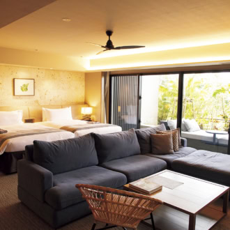 グランディスタイル 沖縄読谷ホテル＆リゾート。78平米のグランディスイート。ゆったりしたL字ソファに加え、テラスには特大のデイベッドもあり、ラウンジから戻ったらお昼寝タイムにしても。ベッドはシモンズで極上の寝心地。