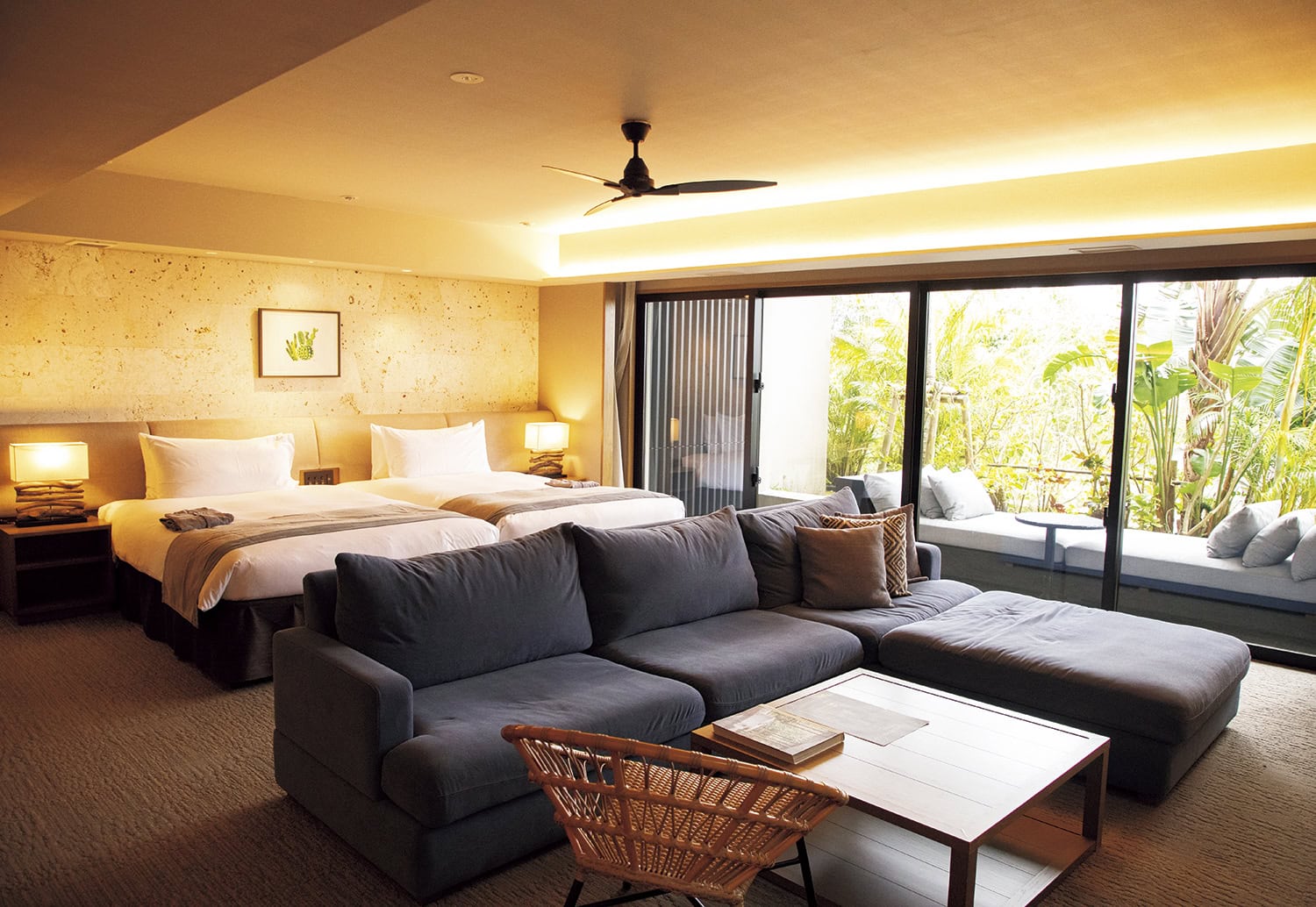 グランディスタイル 沖縄読谷ホテル＆リゾート。78平米のグランディスイート。ゆったりしたL字ソファに加え、テラスには特大のデイベッドもあり、ラウンジから戻ったらお昼寝タイムにしても。ベッドはシモンズで極上の寝心地。